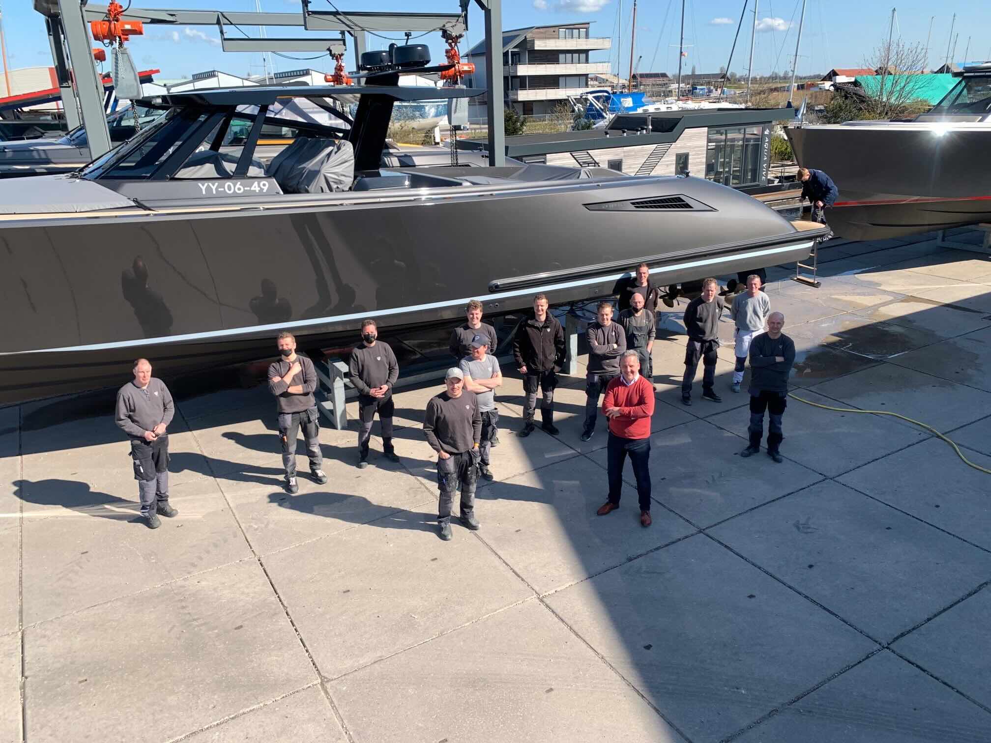 Medewerkers staan bij een groot jacht op de werf.