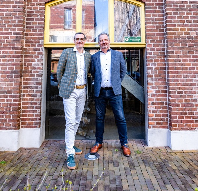 Jeroen Gerrits en Arie Pieter van Wensveen staan samen voor de ingang van een gebouw.