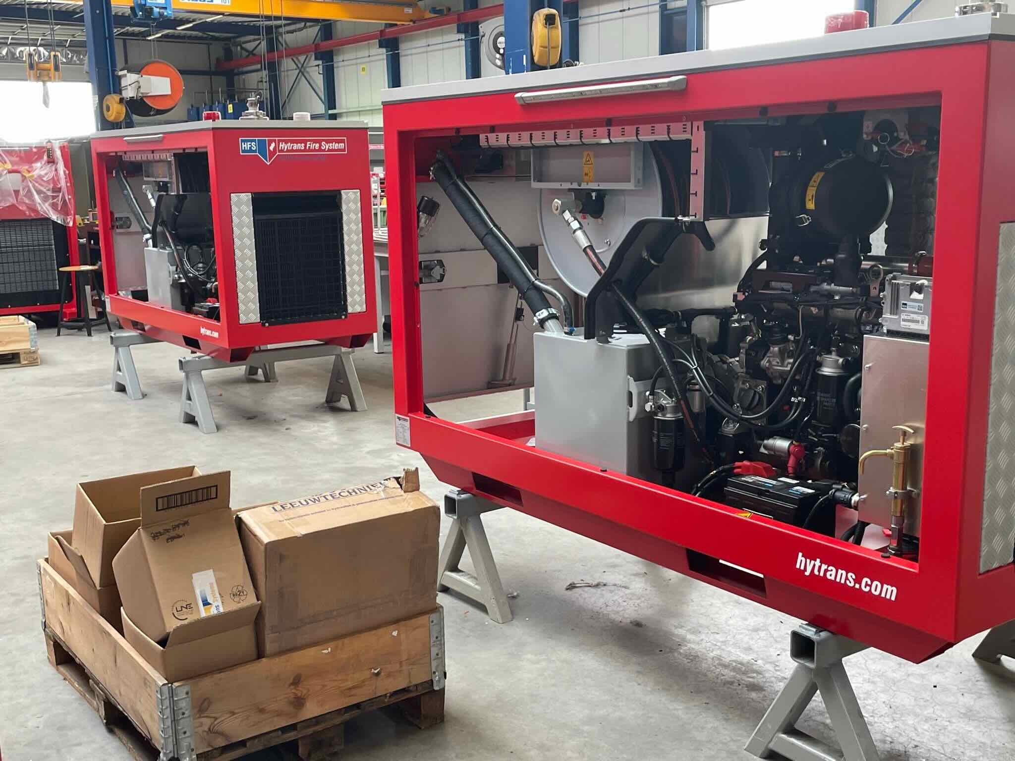 Rode machine-units staan opgesteld voor assemblage in een werkplaats.