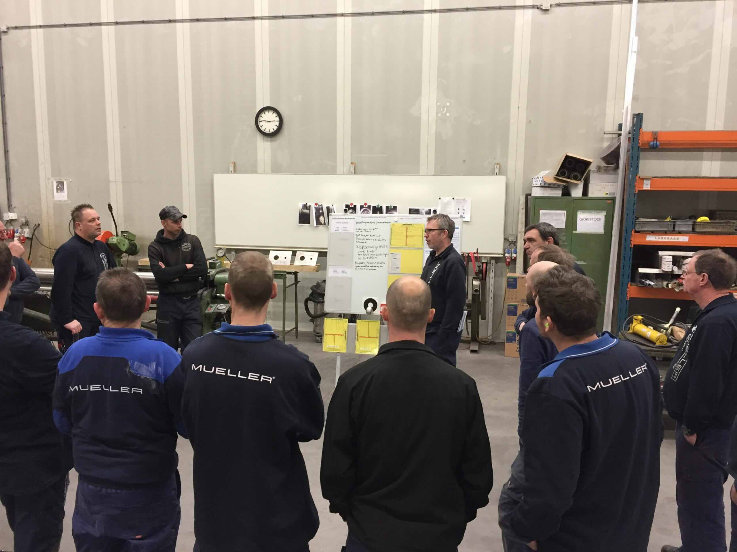 Medewerkers van Müller Tankbouw bespreken verbeterpunten bij een bord in de werkplaats.