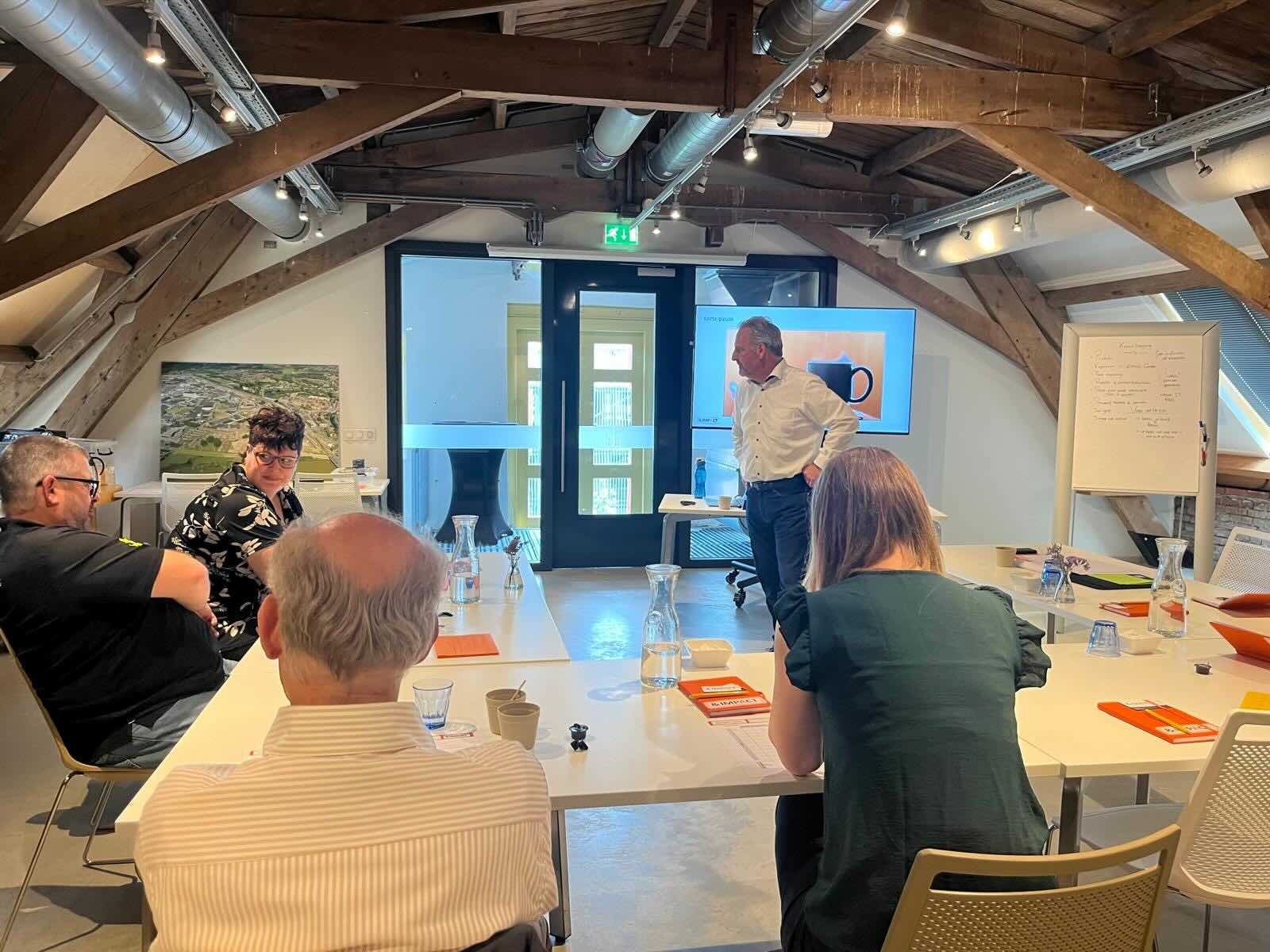 Trainer bespreekt een onderwerp met deelnemers in een trainingsruimte.