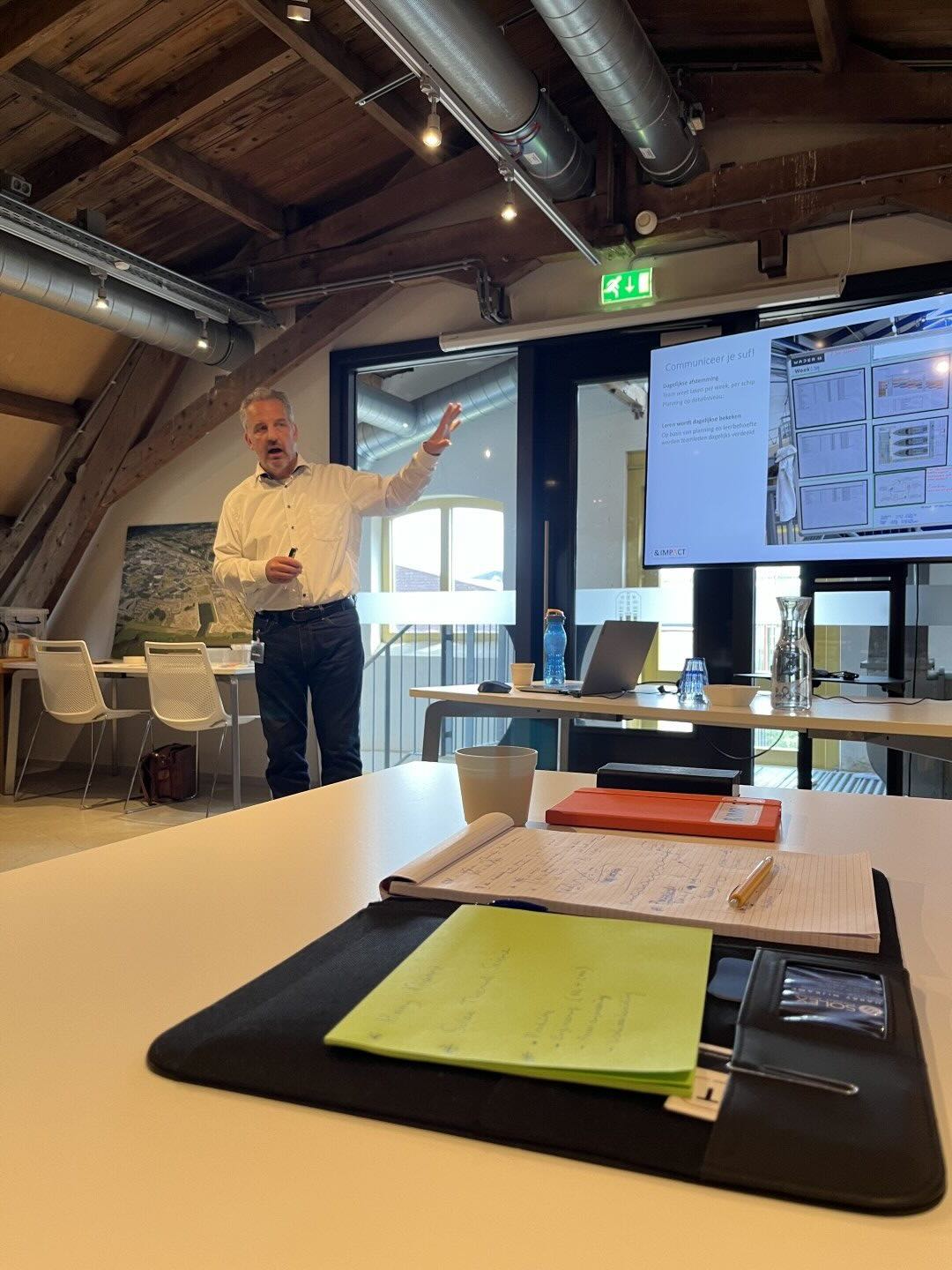 Trainer geeft uitleg aan deelnemers bij een scherm met planningsborden.