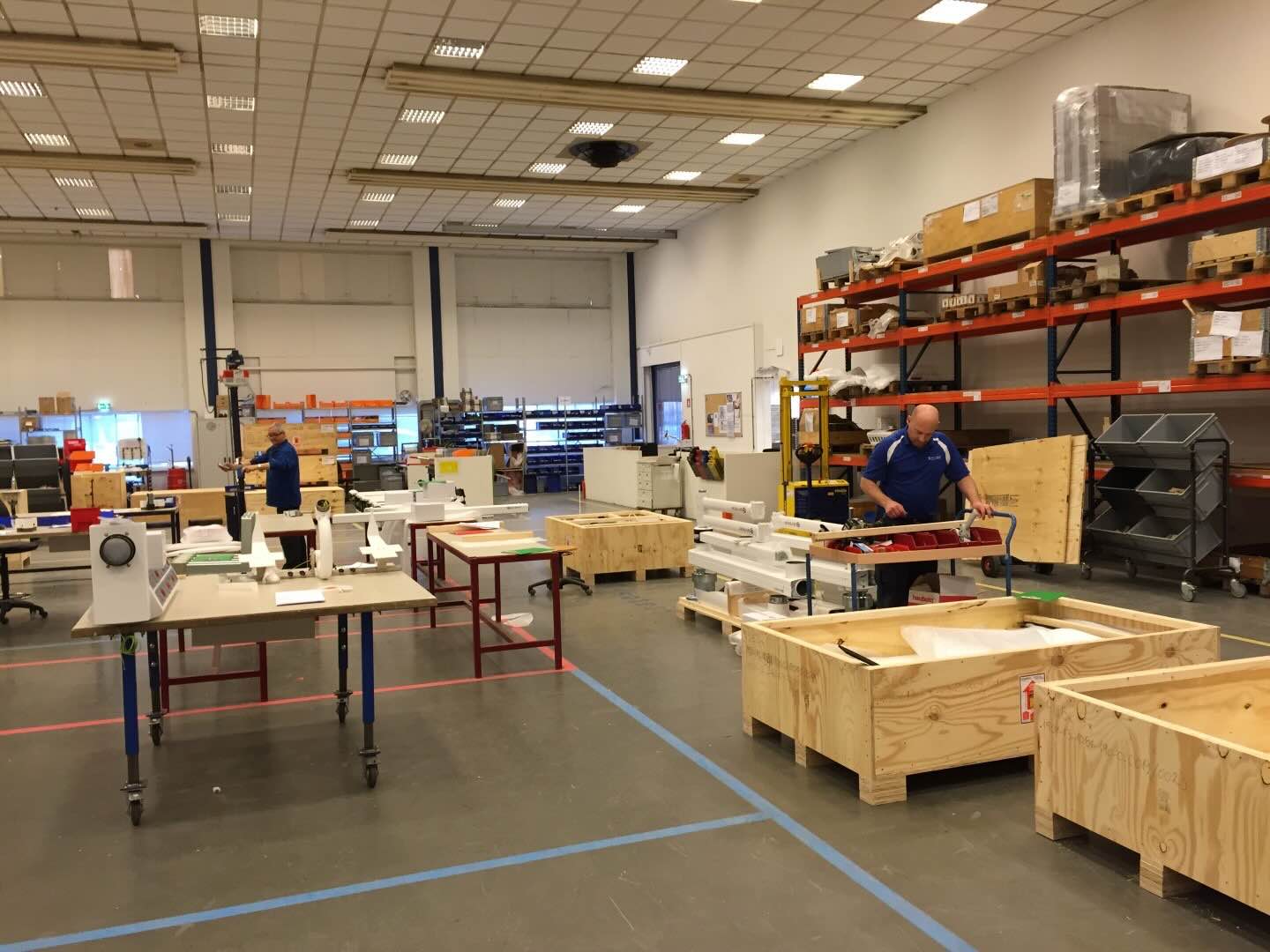 Medewerkers werken aan onderdelen in een ruime productie- en assemblagewerkplaats.