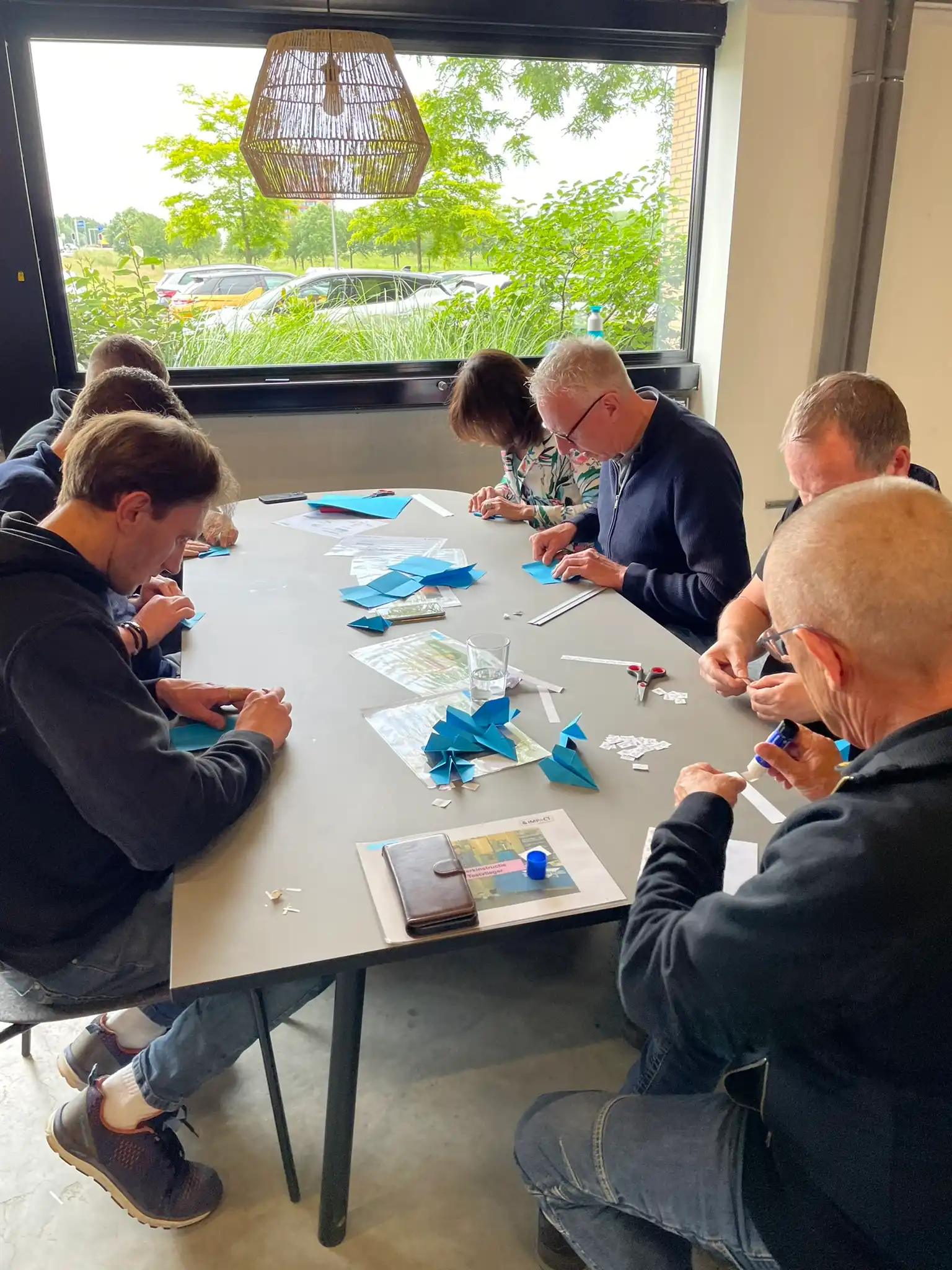 Deelnemers vouwen papieren vliegtuigjes tijdens een Yellow Belt-oefening.